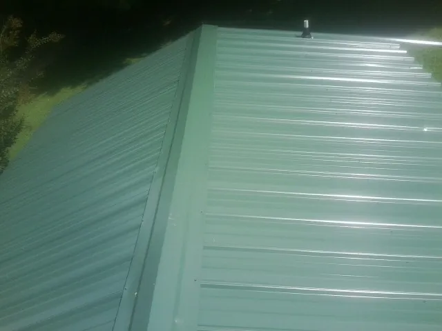 New green metal panels meeting at the ridge of a roof — Flat Roof Repair work by our crew in Poway