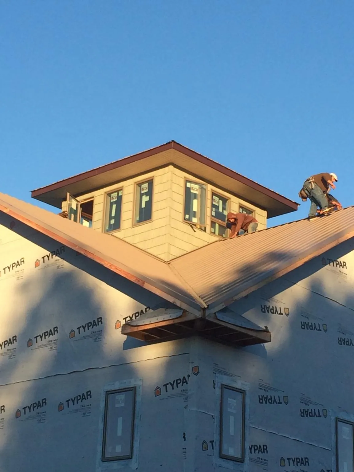 Roofers working around a rooftop cupola on a new metal roof at sunset — Roof Waterproofing in Poway by Roofing Brothers